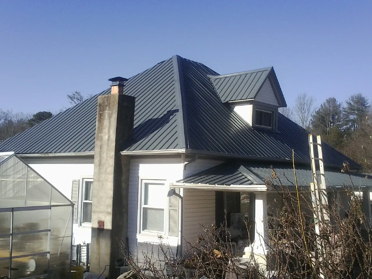Dark blue standing seam metal roof on a white farmhouse with dormer — Slate & Tile Roof Repair by Roofing Brothers in Oak Park