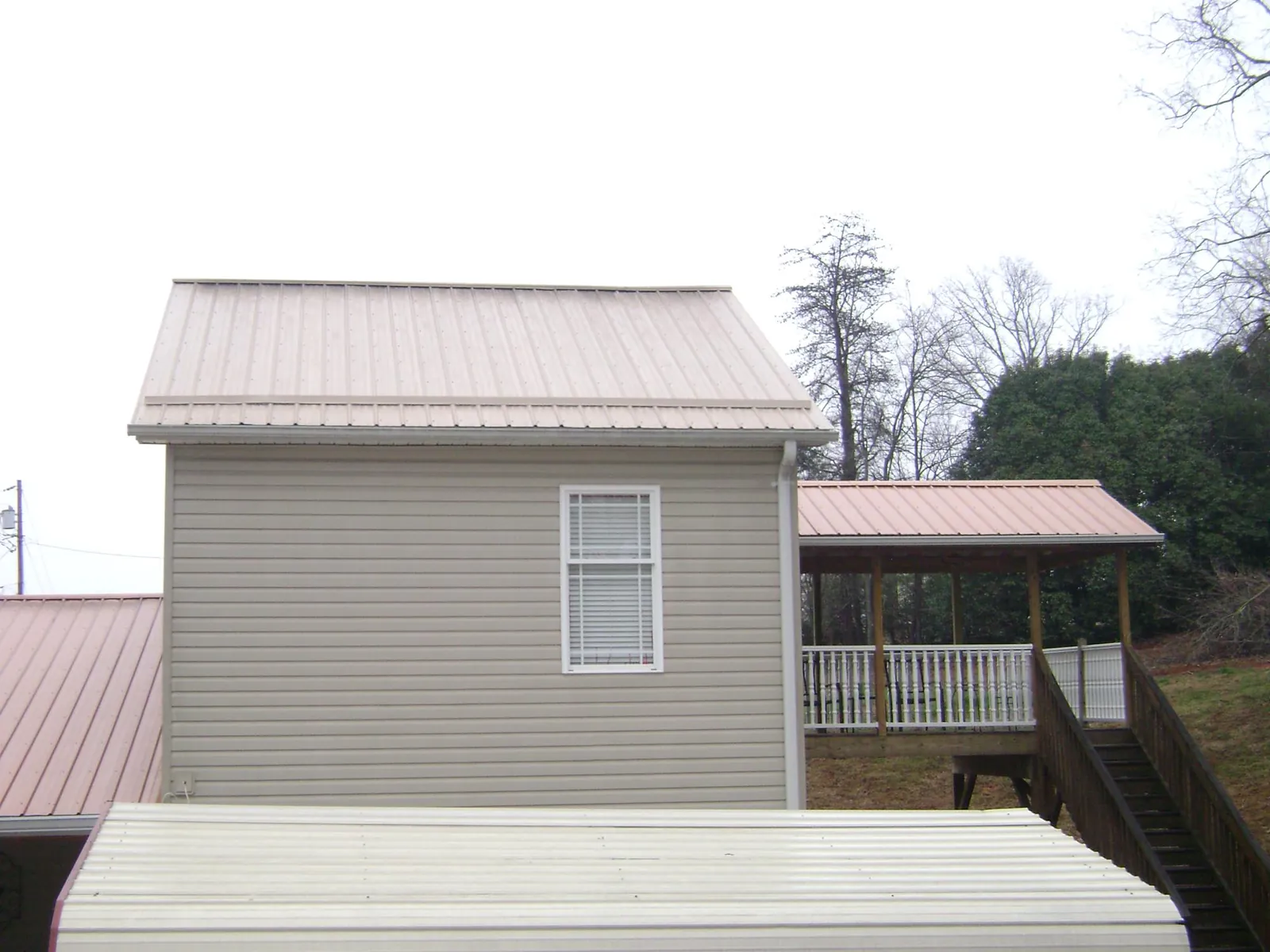 Tan metal roofs on a two story addition and attached porch, from a Roof Replacement job in Oak Park